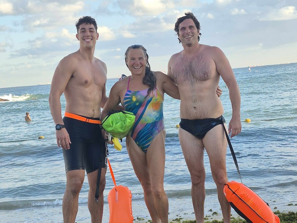 Audrey with two swimmers on the beach after an open-water swim